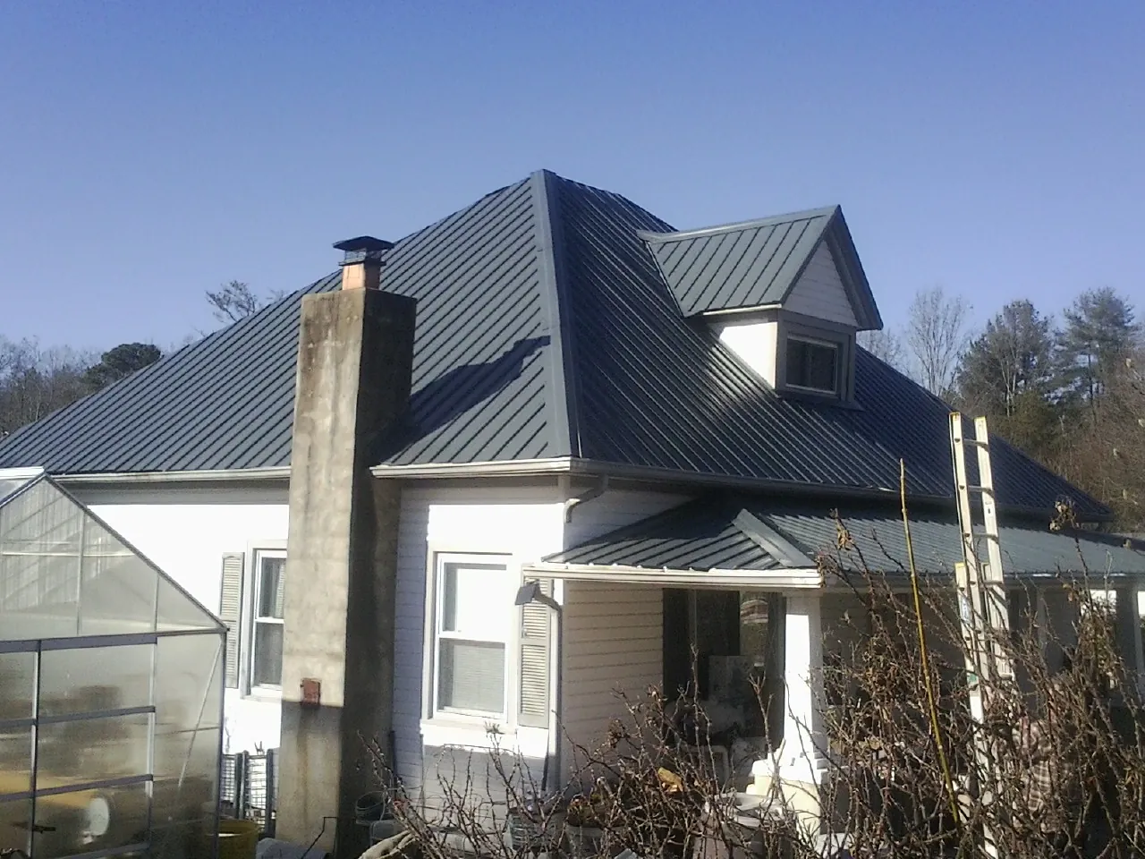 Dark blue standing seam metal roof on a white farmhouse with dormer — Slate & Tile Roof Repair by Roofing Brothers in Lilly
