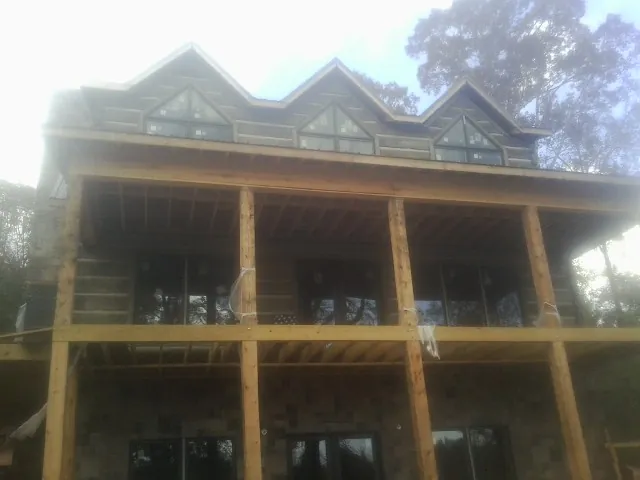 Dormers and porch framing on a large log home under construction — Roof Coating work by our crew in Lilly