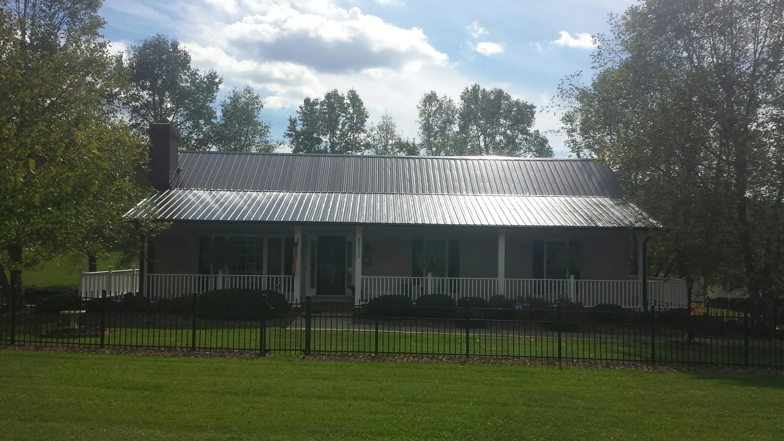 Gray metal roof on a brick ranch with a full width front porch — Gutter Guard Installation work by our crew in Lilly